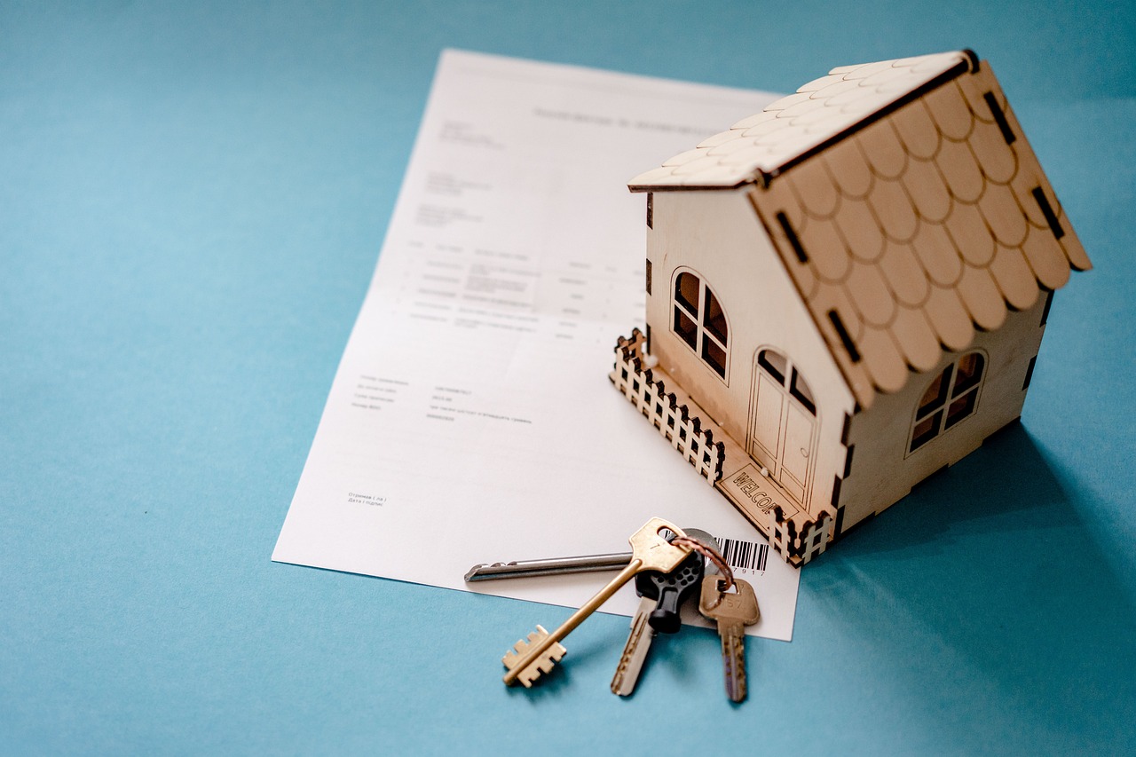 A model home with keys resting on closing paperwork